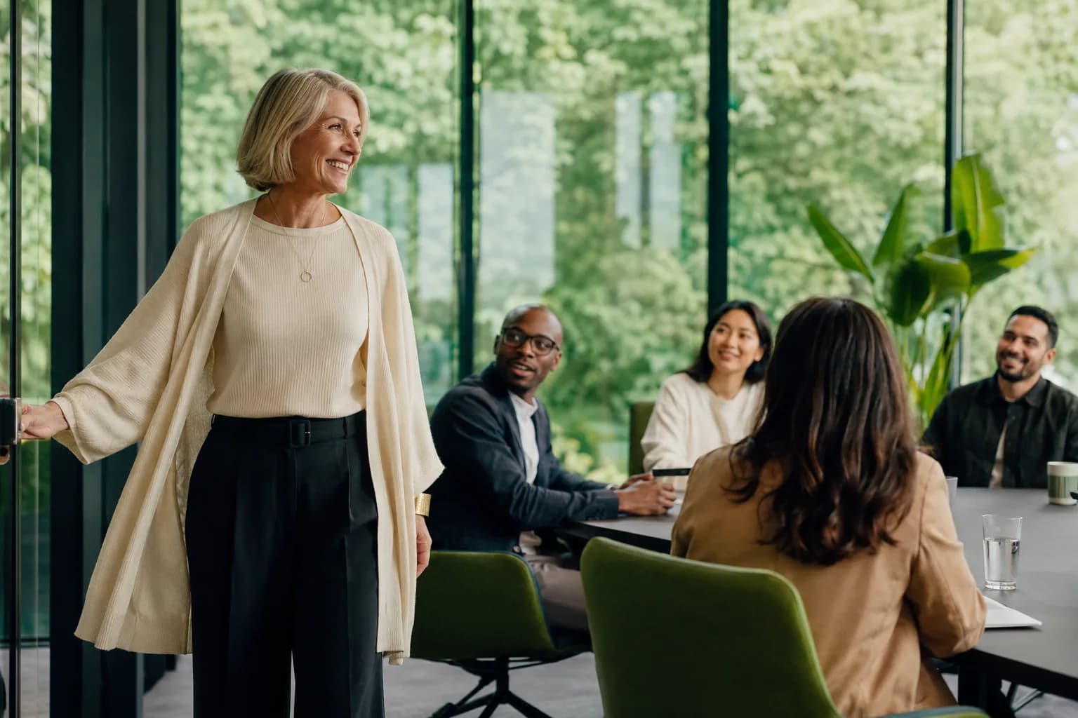 A founder entering a bright glass-walled boardroom to visible recognition, showing how closing the visibility gap makes a capable expert the known one.