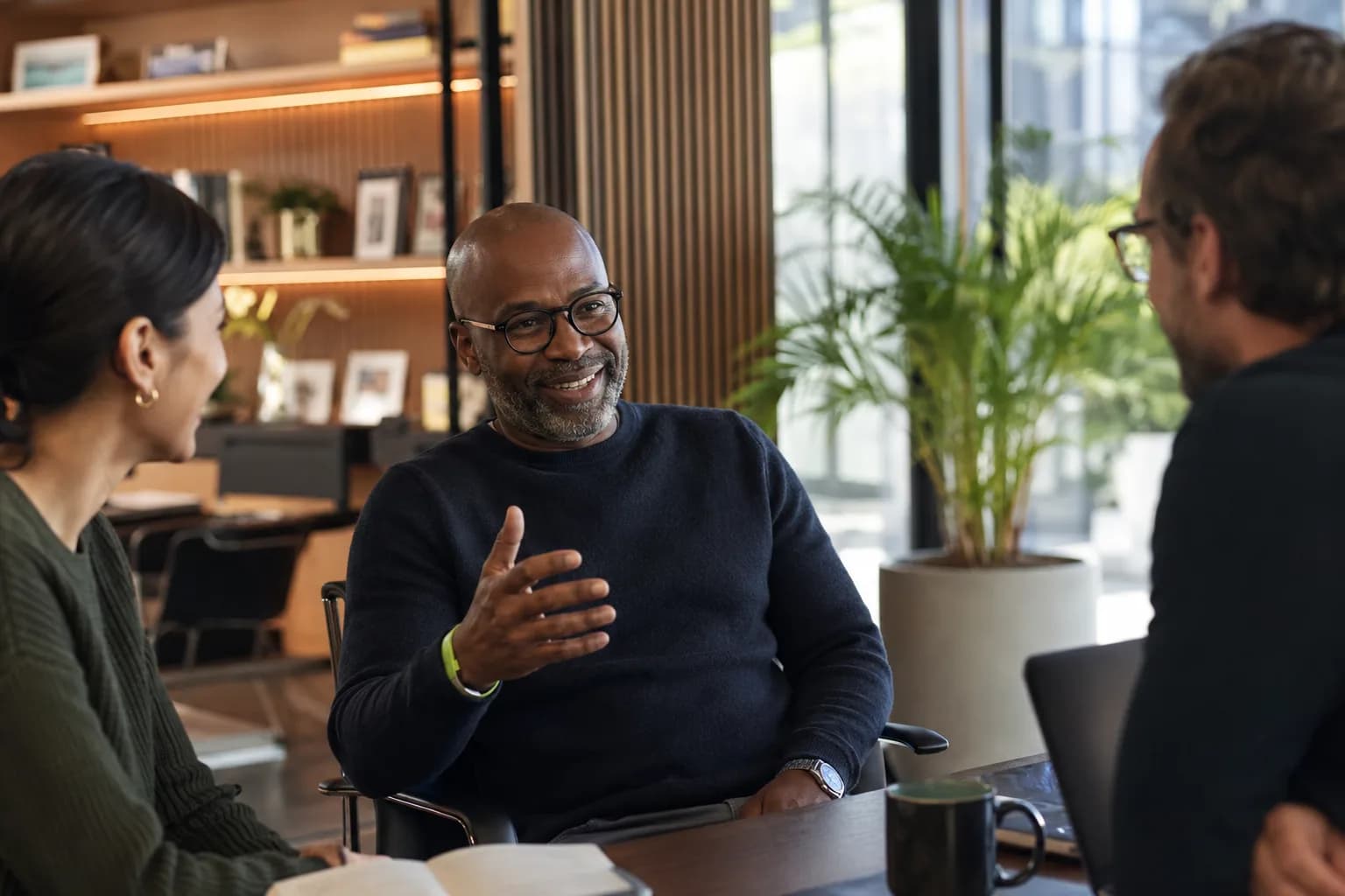 A grounded founder in genuine conversation with his team in a real working office, illustrating the operator credibility that sets a founder apart from an influencer.