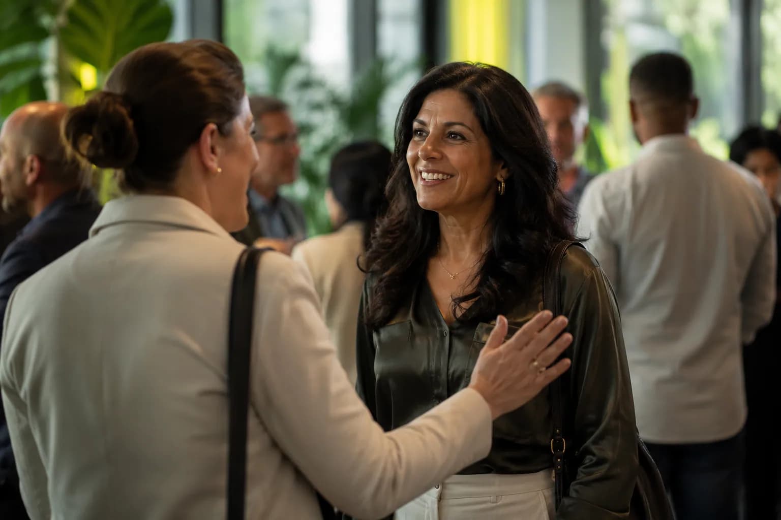 A founder warmly recognized by a peer at a bright networking event, showing how a track record of strong podcast appearances turns into earned authority.