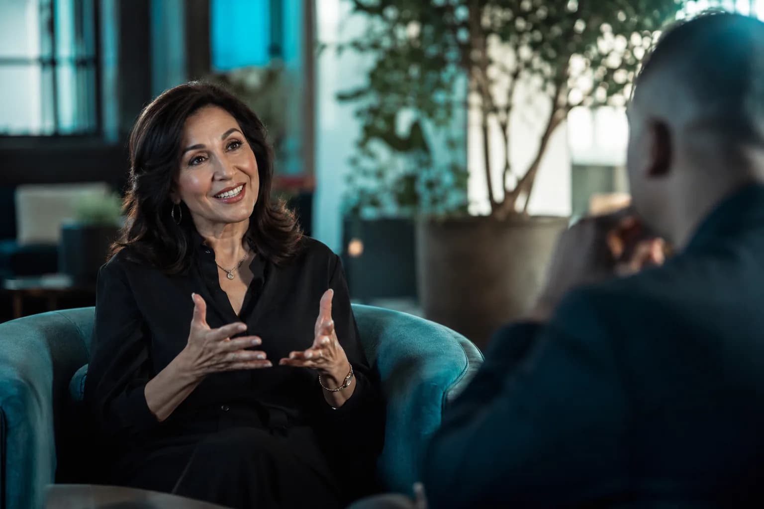 A poised strategist mid-feature interview in a bright modern studio, showing how sharp positioning reverses the pitch so the market comes to her.
