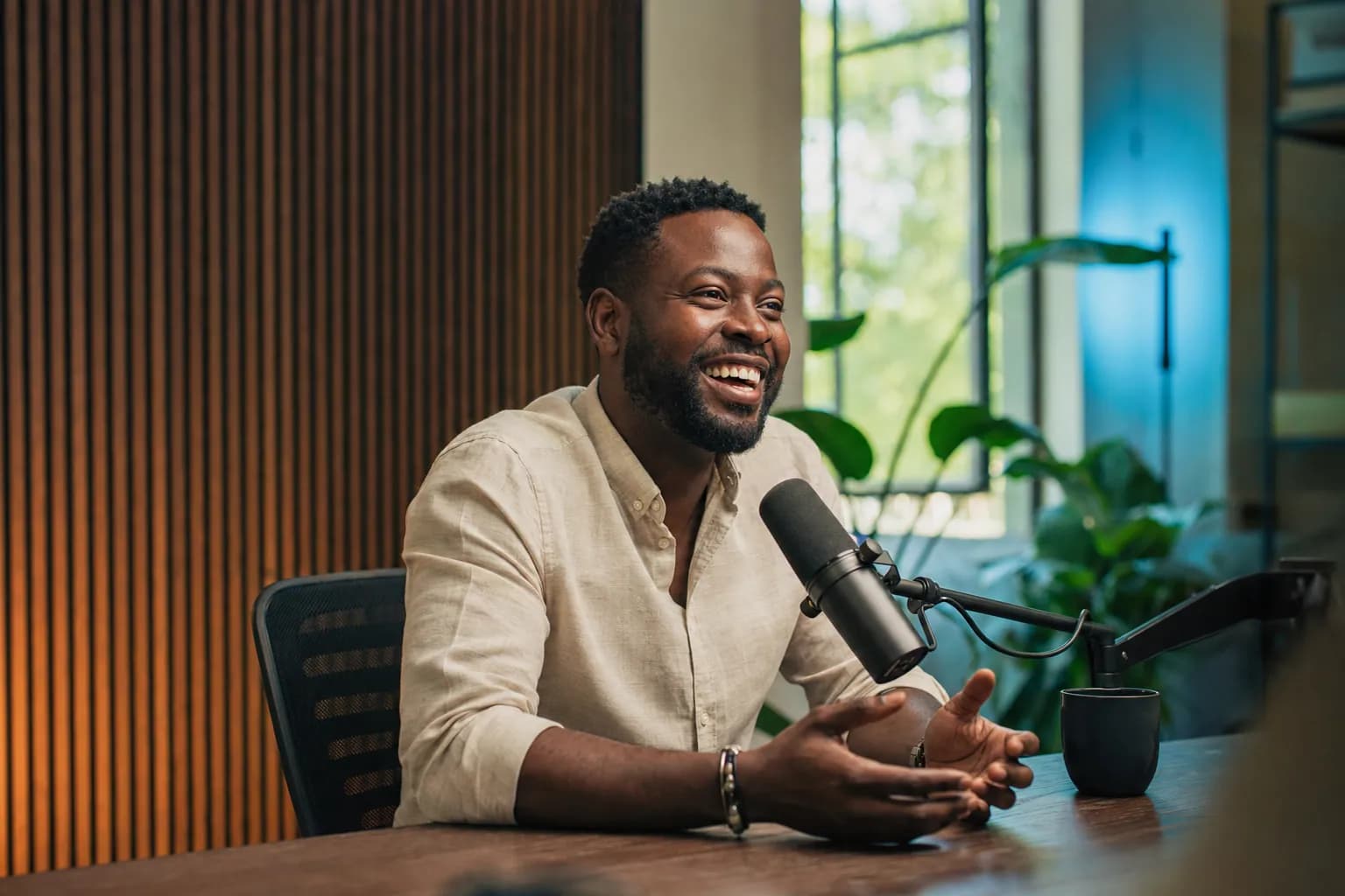 A B2B founder recording a podcast episode in a bright modern studio, leaning into the microphone mid-conversation, the kind of visible appearance buyers research before they reach out.