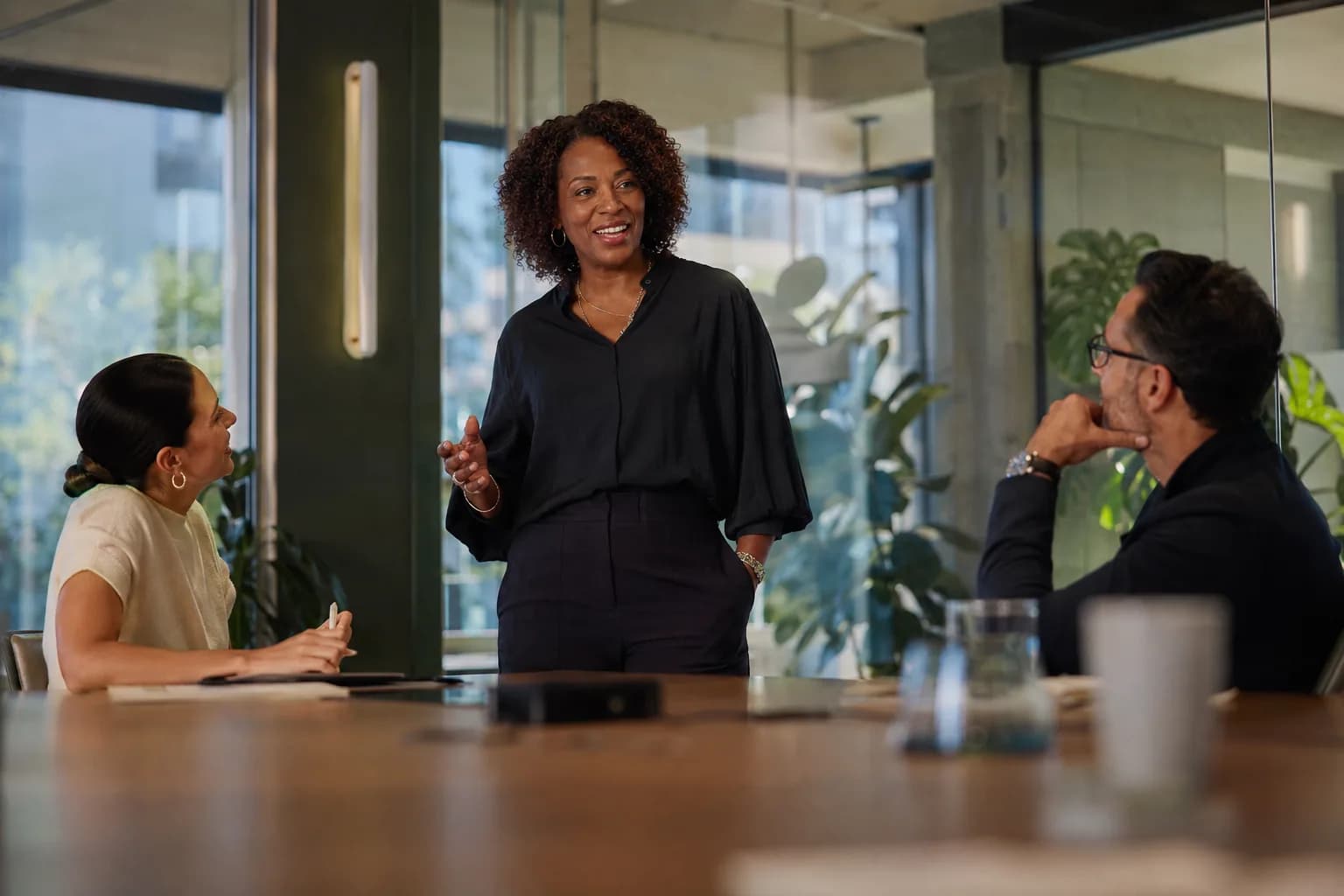 An accomplished executive confidently leading a discussion with colleagues in a bright modern boardroom, showing how assembled credibility flips inbound from chasing to being chased.