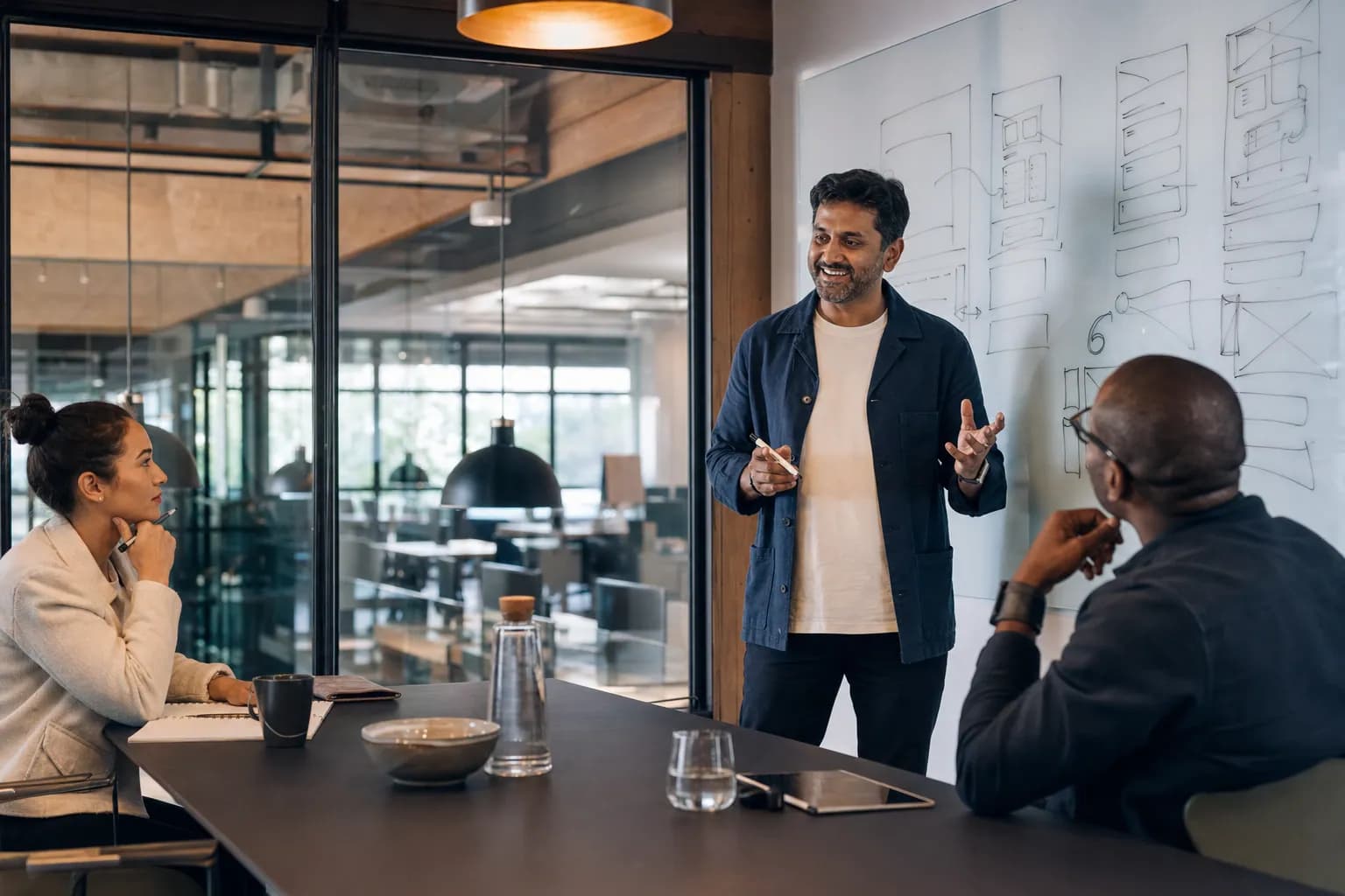 A founder leads an authority positioning for founders strategy session in a glass-walled conference room, pressure-testing the defensible category his content will compound around.