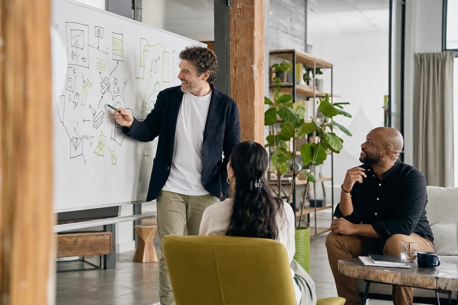 A founder works with a personal branding agency team at a whiteboard, mapping how one documented Brand DNA governs every brand surface consistently.